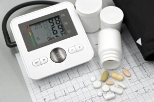 Blood pressure monitor with pills on ECG sheet, essential for heart health management.