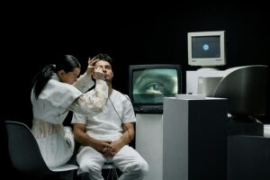 A woman performs an eye examination on a man in a vintage tech lab.